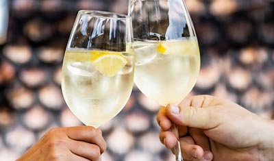 Zwei Gäste stoßen mit einem Aperitif im Weinglas an